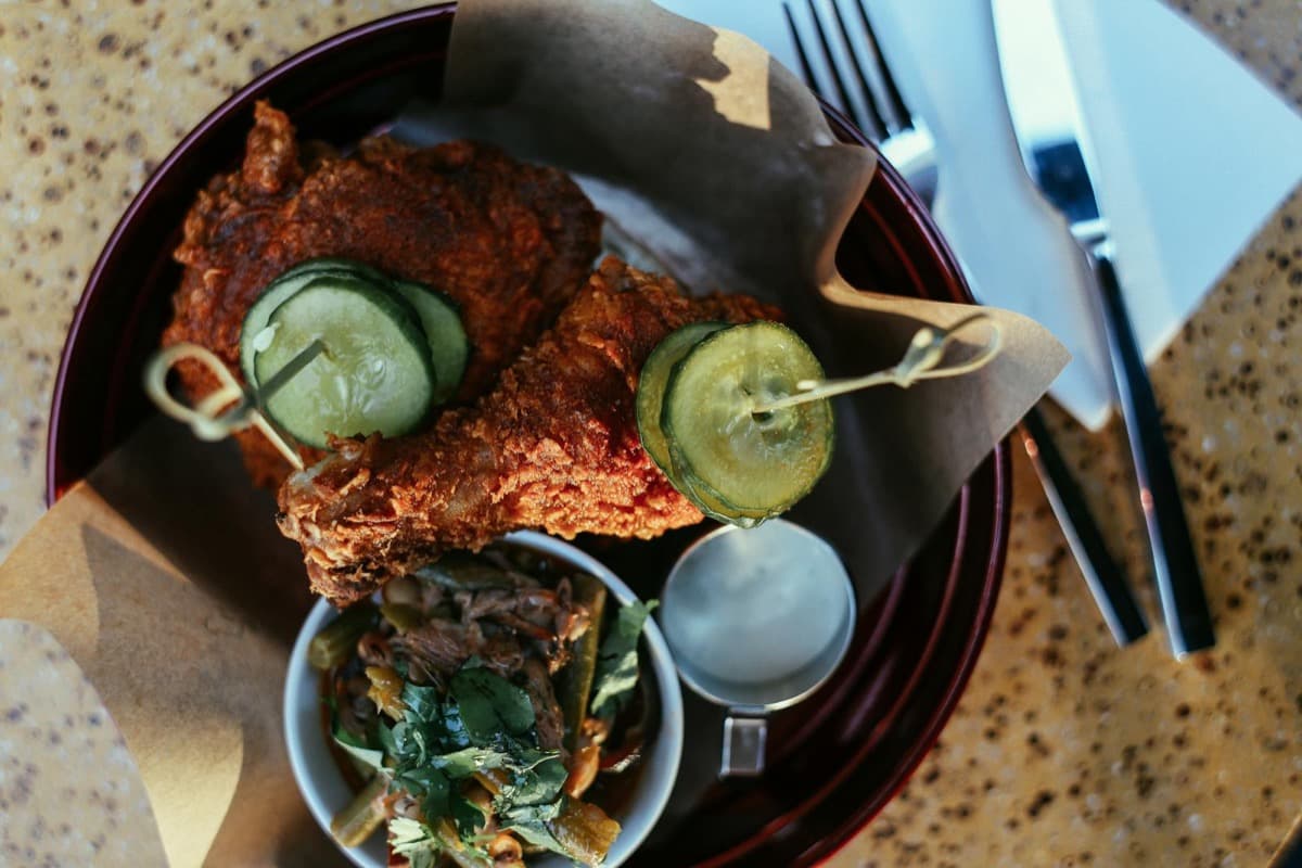 Golden Southern fried chicken with cucumber garnish and a side of greens and beans (16:9)