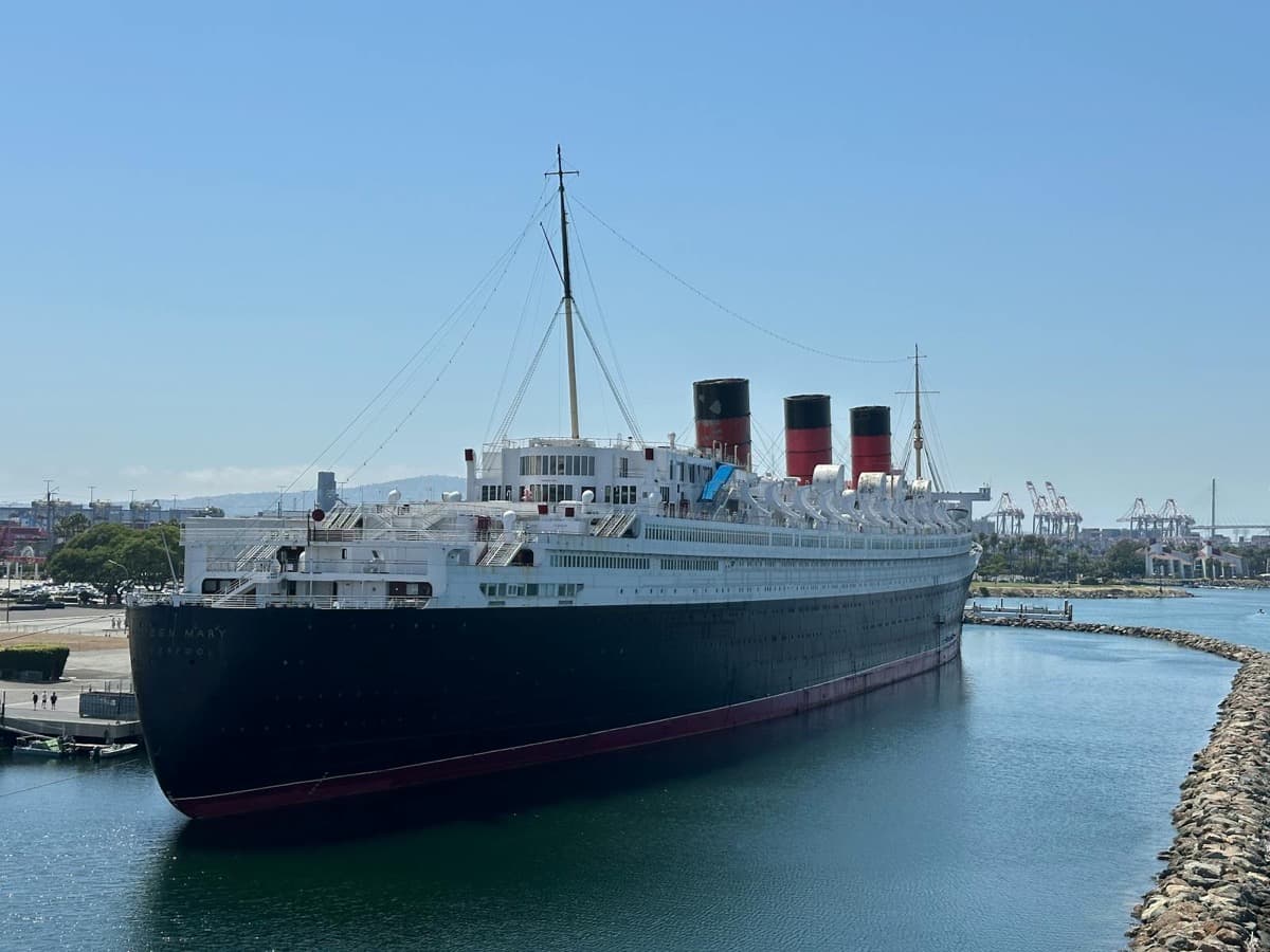 A classic black-and-white ocean liner with red funnels docked at a harbor (16:9)