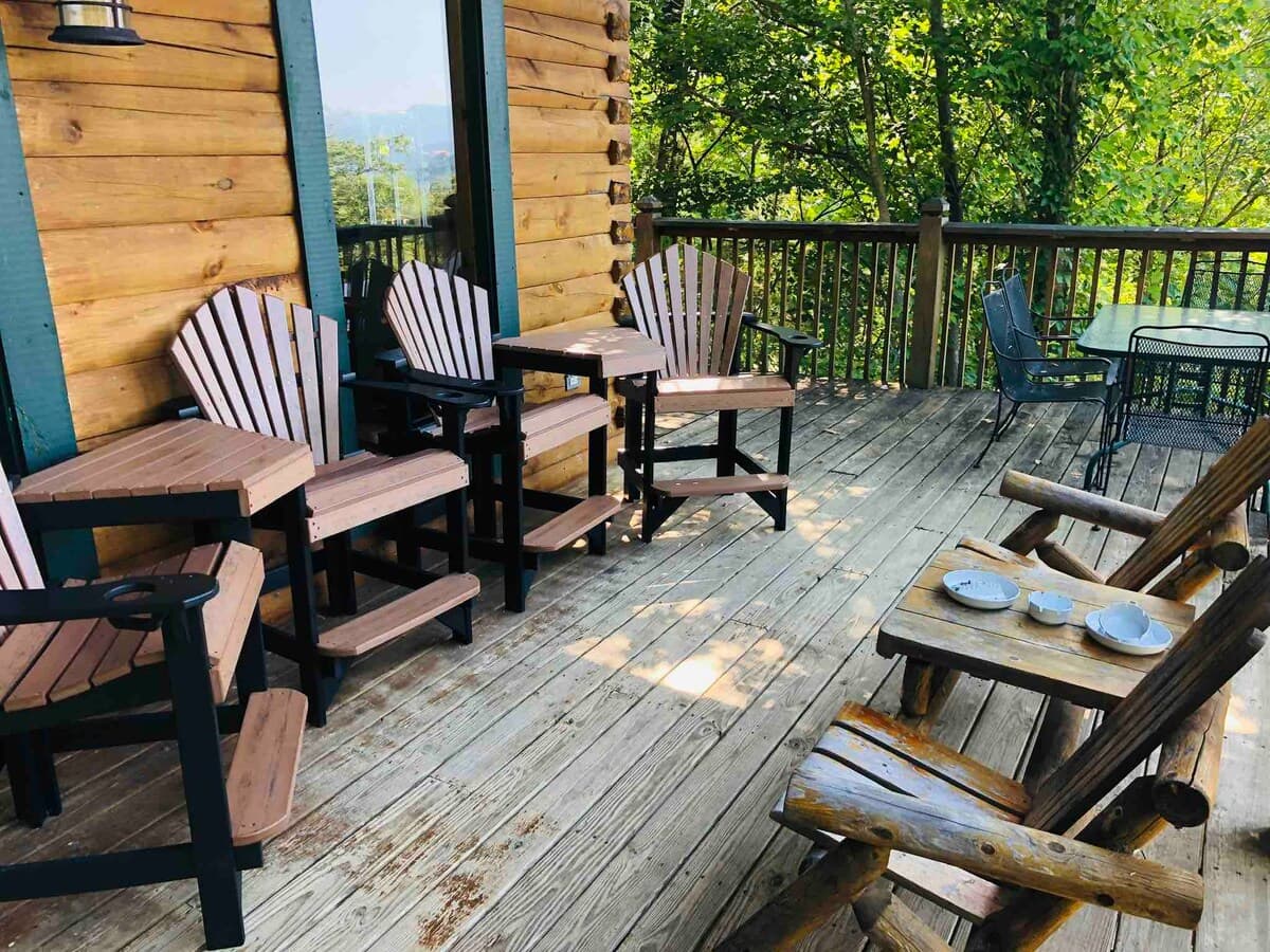 Upper deck with Adirondack chairs, bistro dining set, and mountain views through the trees