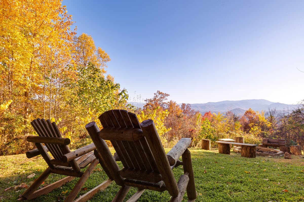Wooden Adirondack chairs overlooking Smoky Mountain views with golden fall foliage
