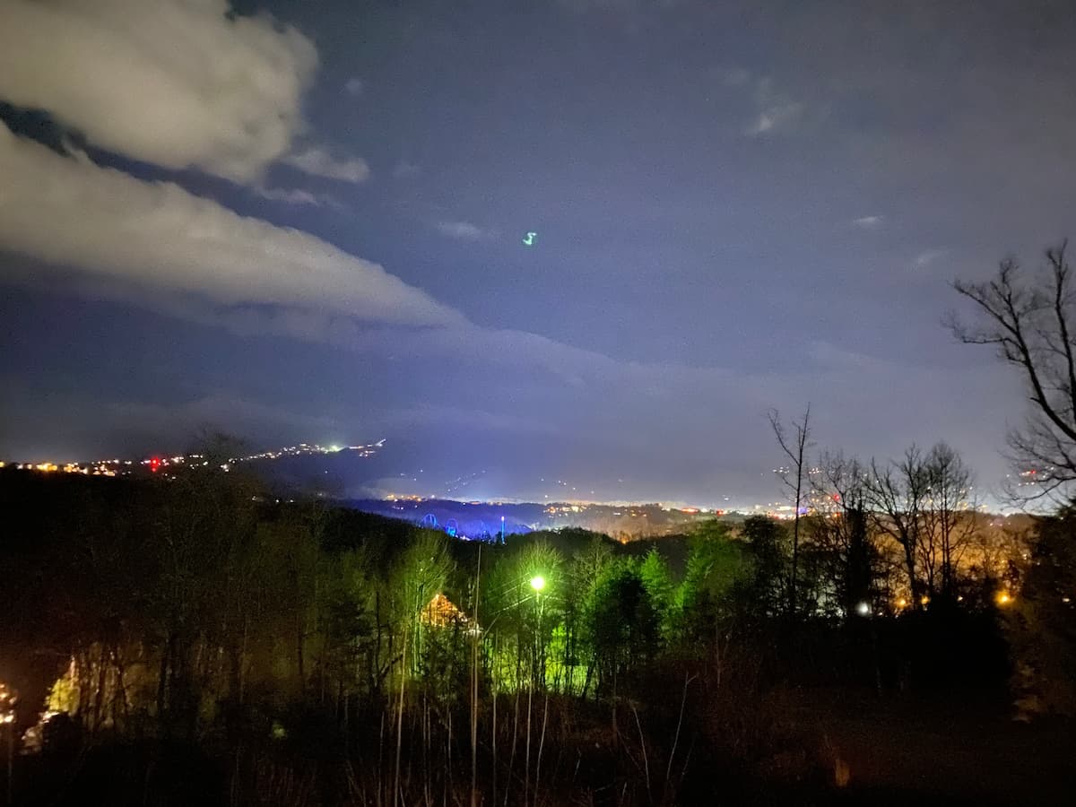 Night view of Pigeon Forge, Dollywood, and Gatlinburg city lights glowing through valley haze from the deck