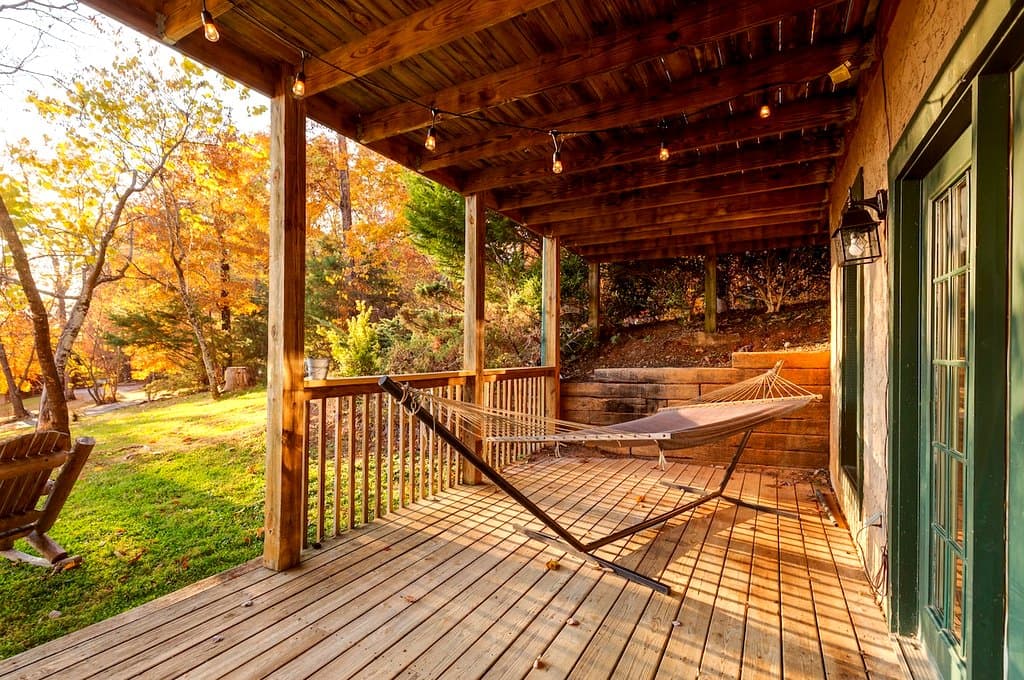 Hammock on a covered cabin deck surrounded by autumn foliage