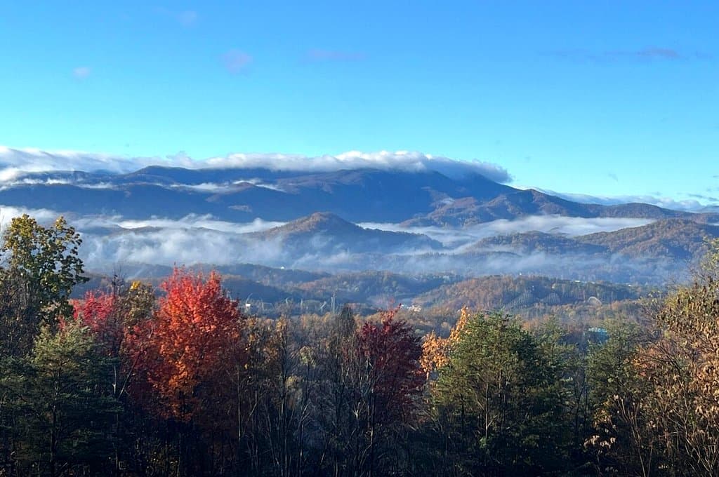 Mist among mountain ridges above autumn trees