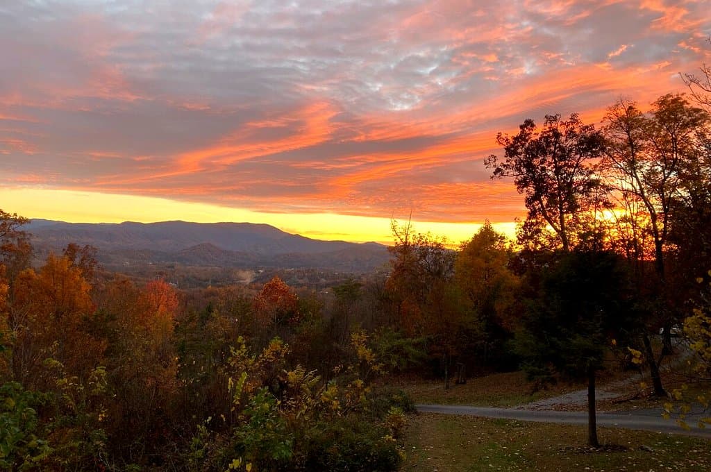 Orange sunset above the cabin yard and wooded mountains
