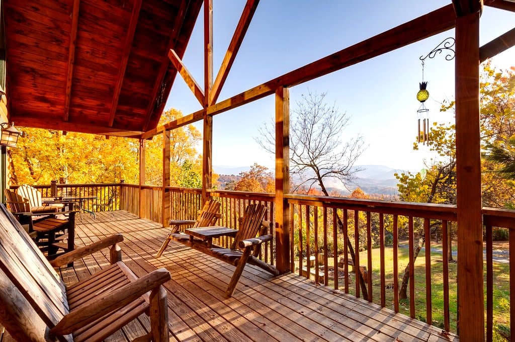 Covered deck with rocking chairs overlooking autumn trees