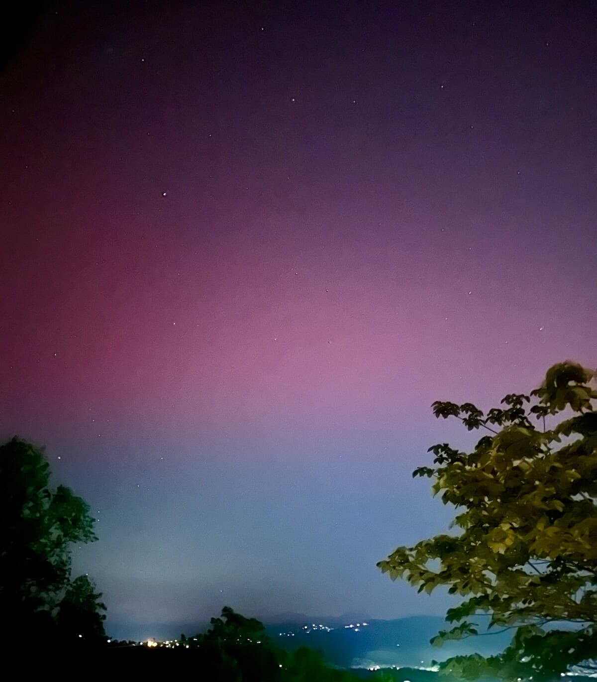 Rare northern lights (aurora borealis) in vivid purple and pink above the Smoky Mountains with stars visible