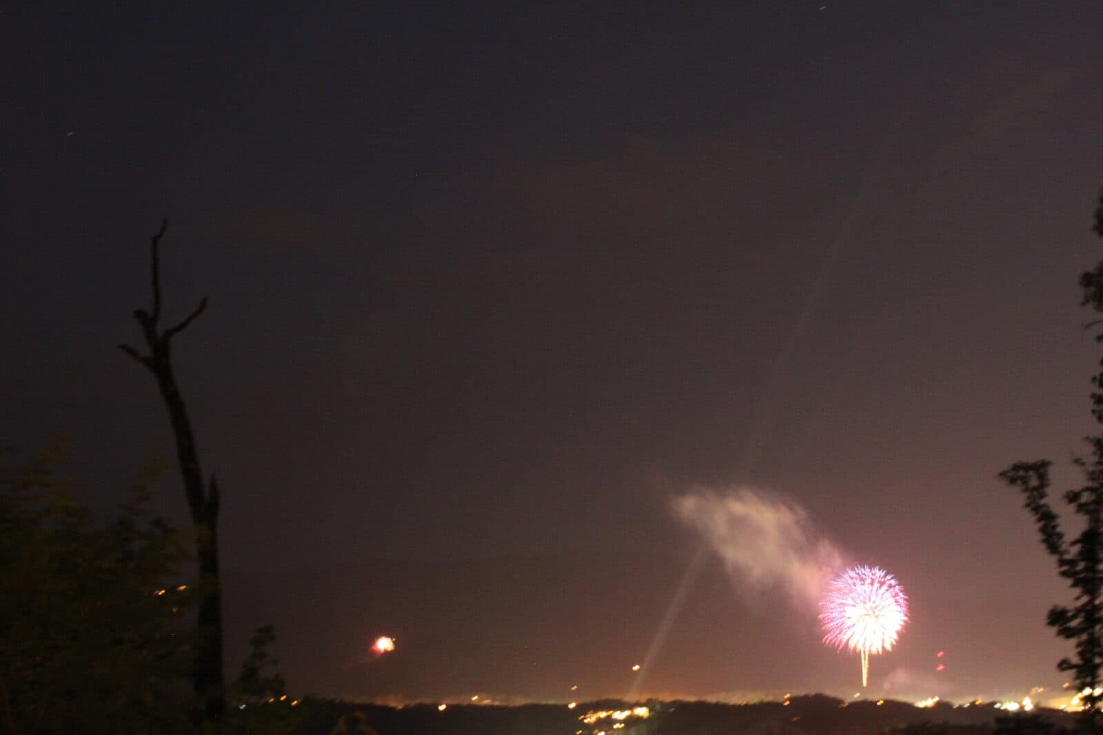 Pink fireworks bursting in the night sky over Pigeon Forge as seen from the Thistle Britches deck