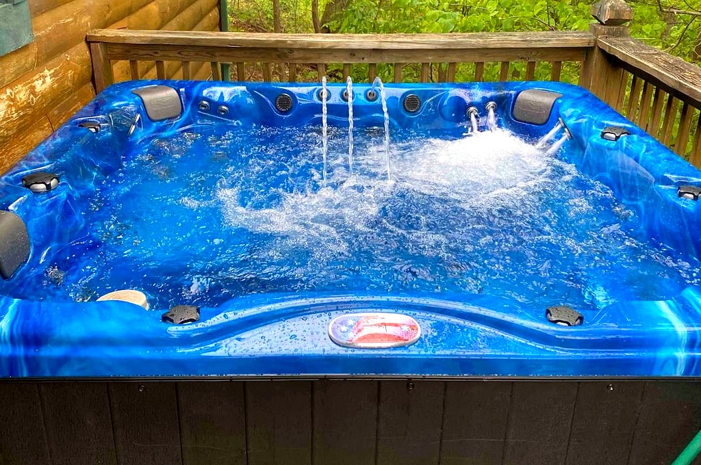 Actual photo from Thistle Britches: Blue hot tub with bubbling water on the cabin deck