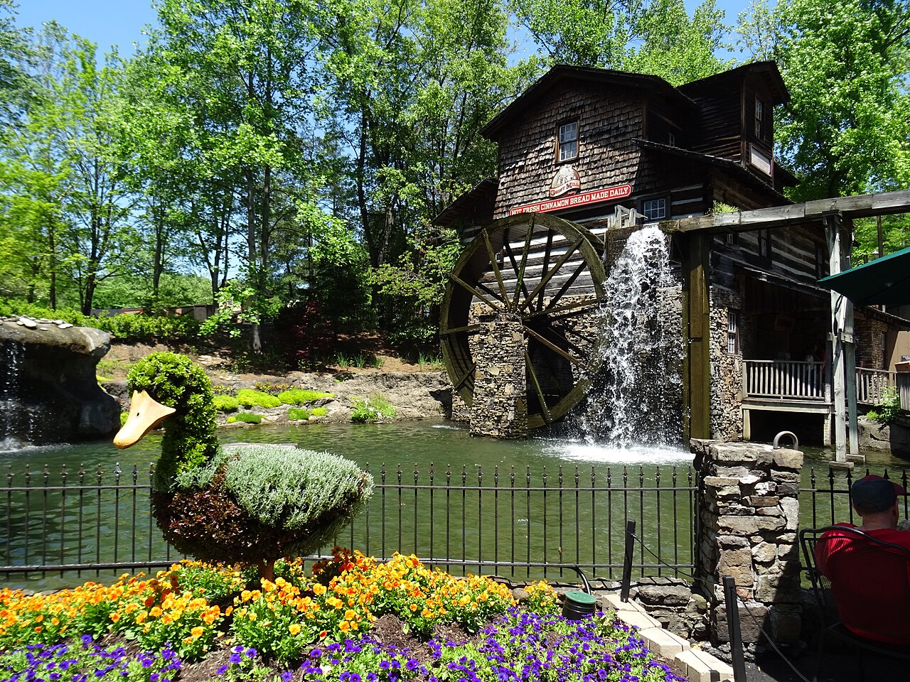 Dollywood's wooden Grist Mill and turning waterwheel beside colorful spring flowers